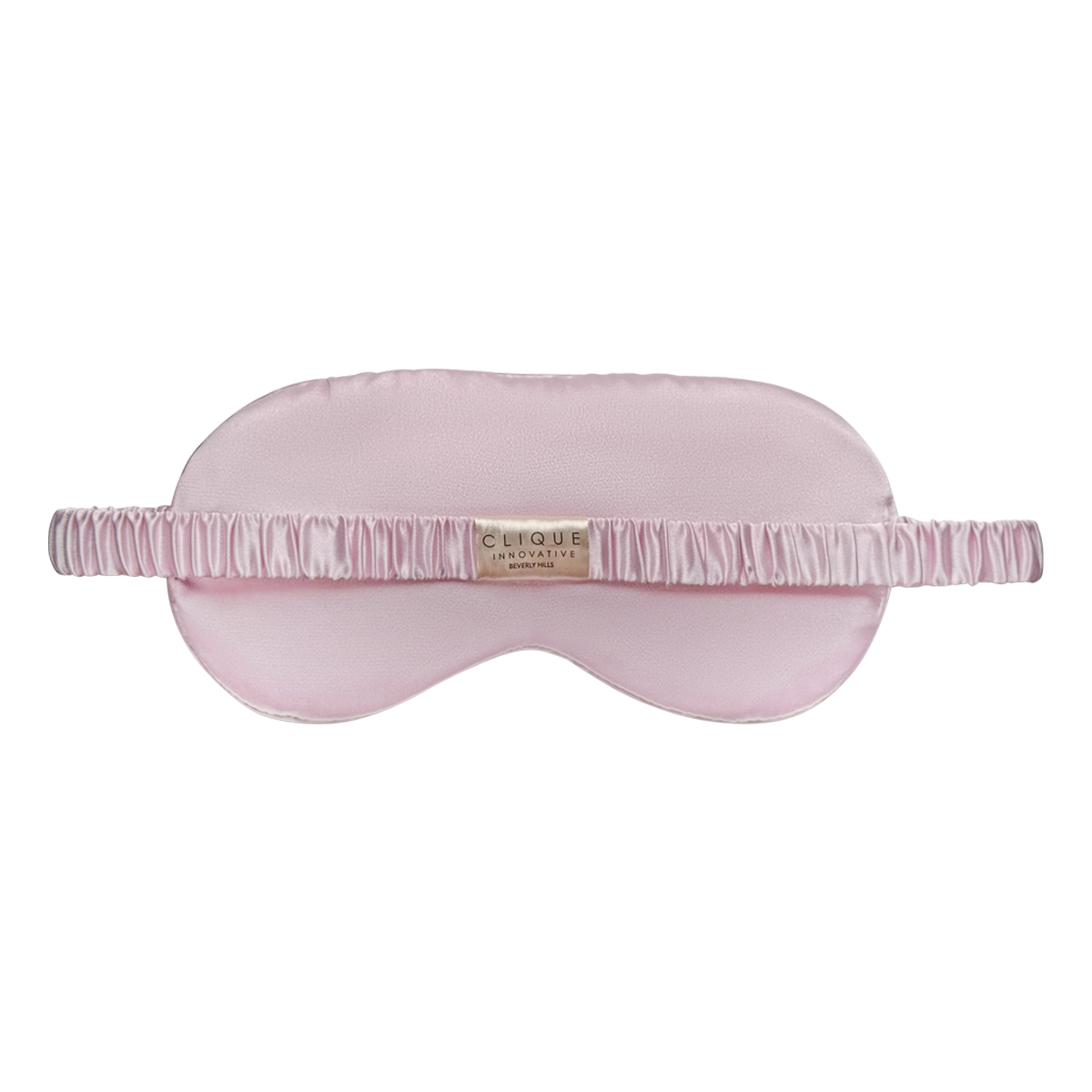 Back view of a light pink satin sleep eye mask with a ruched matching strap and a small “Clique Innovative Beverly Hills” tag at the center, shown on a white background.