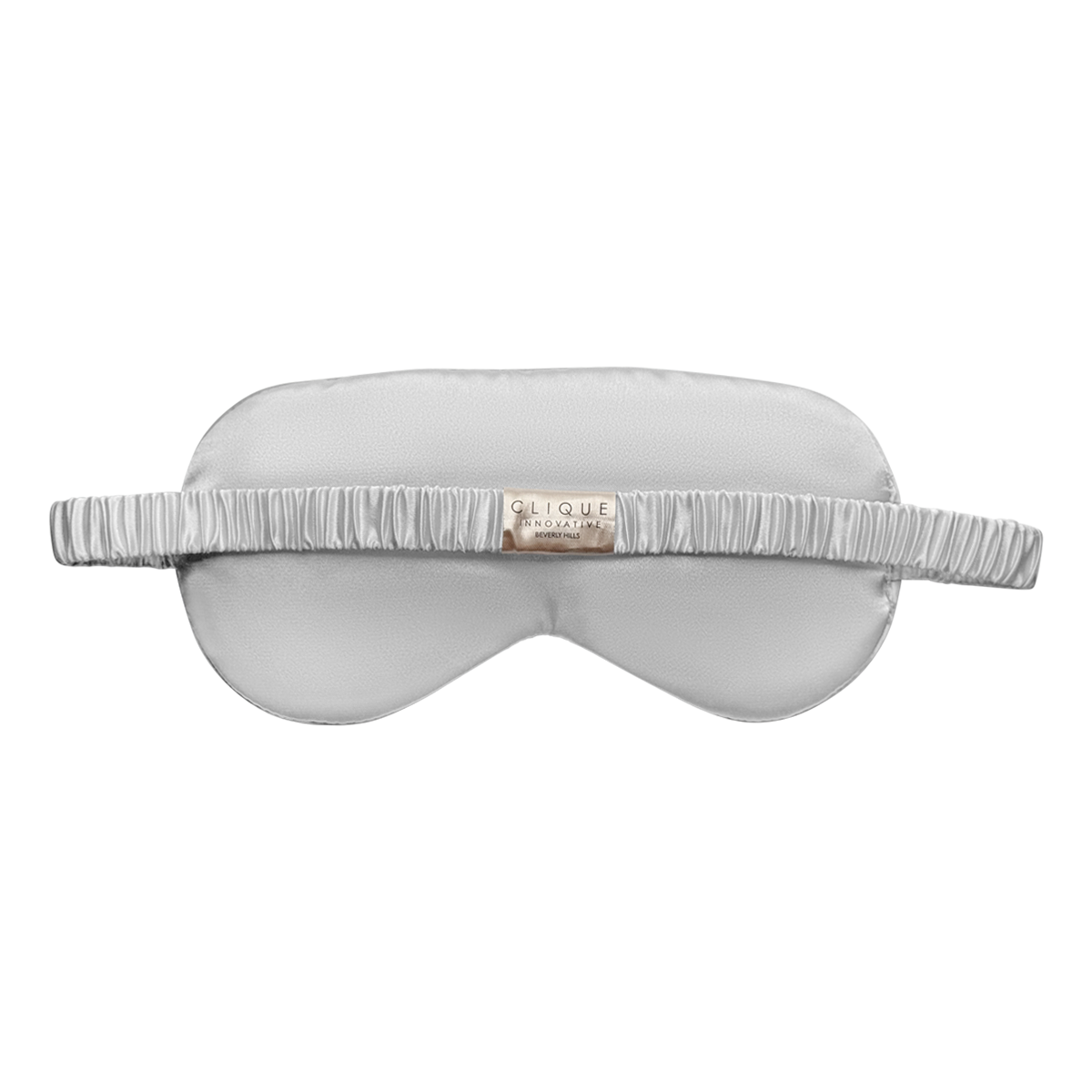 Back view of a silver satin sleep eye mask with a ruched elastic strap and a small 'Clique Innovative Beverly Hills' brand tag, shown on a white background.