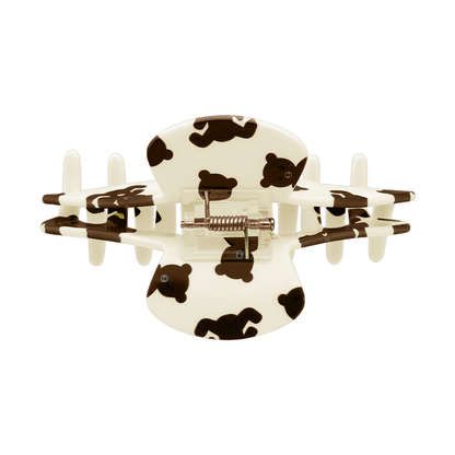 Top view of a beige teddy bear claw clip showing the spring and all-over bear design.