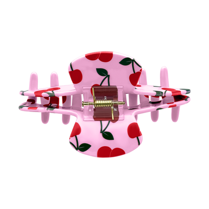Top view of a pink cherry claw clip showing the spring and all-over cherry design.