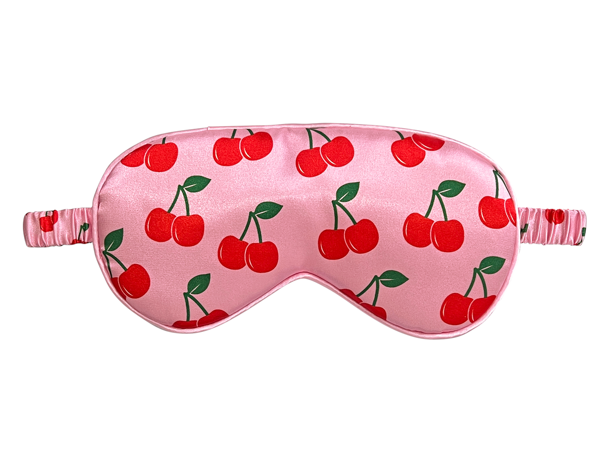 Front view of a pink satin eye mask with an all-over red cherry and green leaf print.