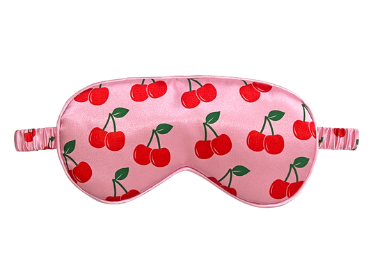 Front view of a pink satin eye mask with an all-over red cherry and green leaf print.