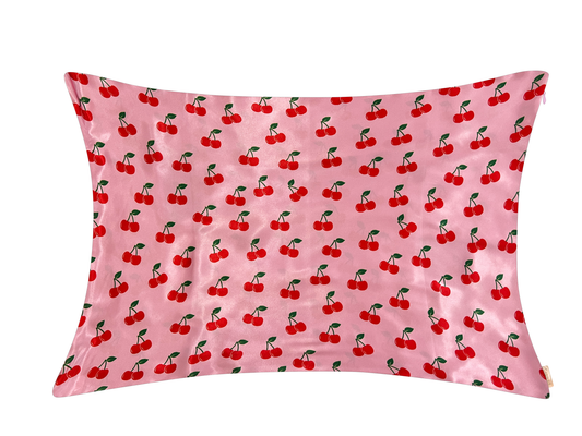 Pink satin pillowcase with an all-over red cherry and green leaf print.