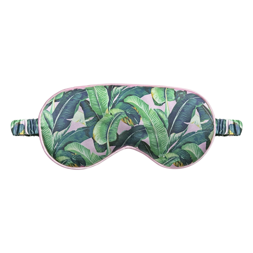 Front view of a tropical banana leaf satin sleep eye mask with soft pink trim and ruched elastic strap, displayed on a white background.