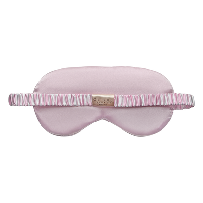 Back view of a light pink satin sleep eye mask with a ruched pink-and-white striped elastic strap and a small “Clique Innovative Beverly Hills” brand label centered on the strap.