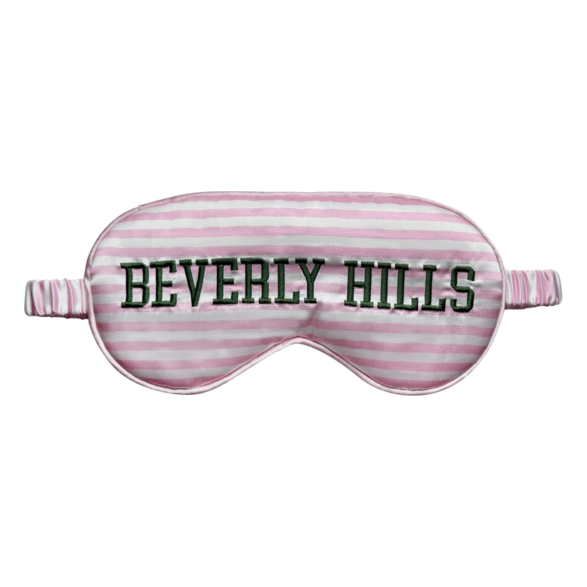 Front view of a pink-and-white striped satin sleep eye mask with “Beverly Hills” embroidered in dark green across the front, shown on a white background.