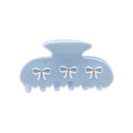 Front view of a light blue claw clip with three white bow graphics and silver rhinestones on a white background.