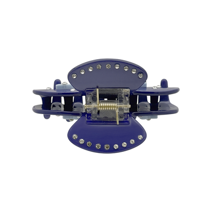 Top view of a dark blue claw clip with clear center hardware, silver rhinestones along the top and bottom edges, and a white background.