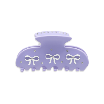 Front view of a light purple claw clip with three white bow graphics and silver rhinestones on a white background.