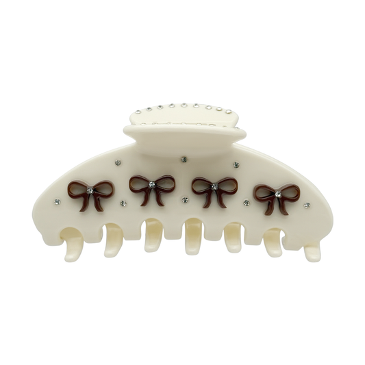 Front view of a beige claw clip with brown bow designs and rhinestone accents
