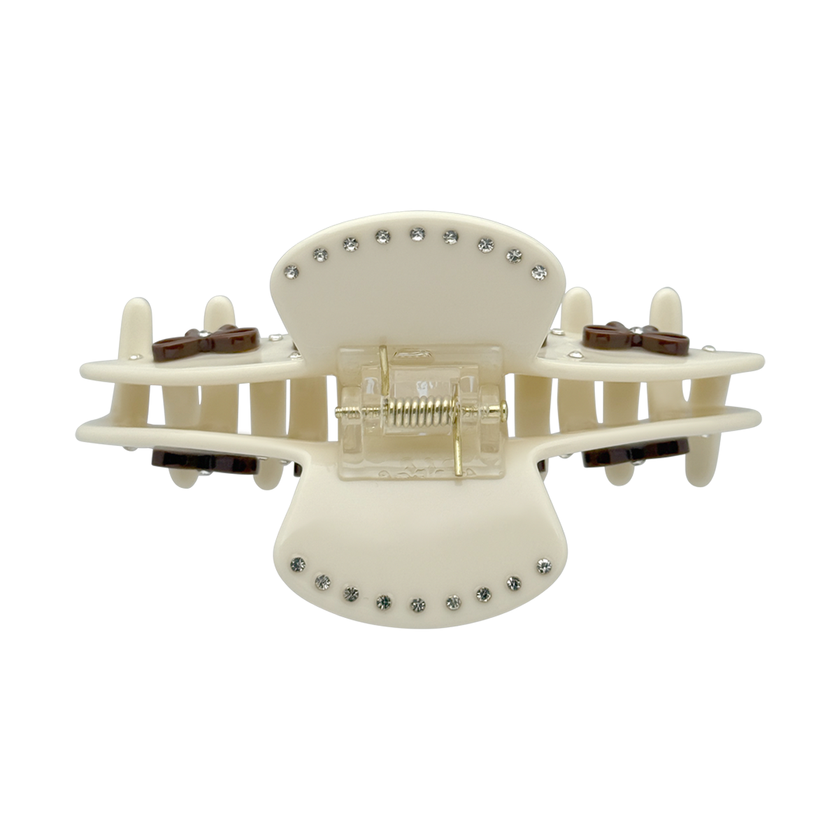 Top view of a beige bow claw clip showing the spring and rhinestone details