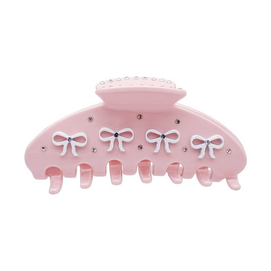 Front view of a pink claw clip with white bow designs and rhinestone accents