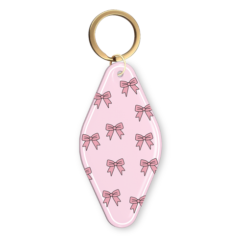 Pink motel-style keychain with an all-over pink bow pattern and a gold key ring.