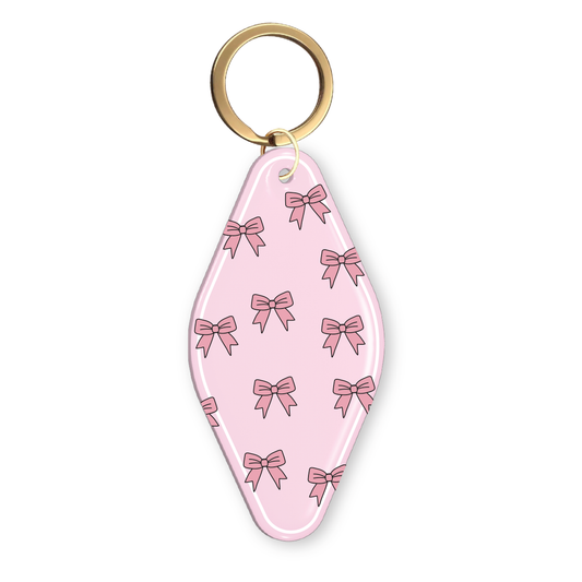 Pink motel-style keychain with an all-over pink bow pattern and a gold key ring.