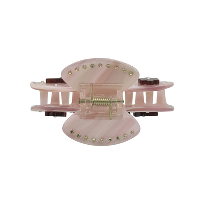 Top view of a rose beige claw clip showing gold rhinestones along the top edges, a gold spring mechanism, and side views of dark brown flower and butterfly graphics on a white background.