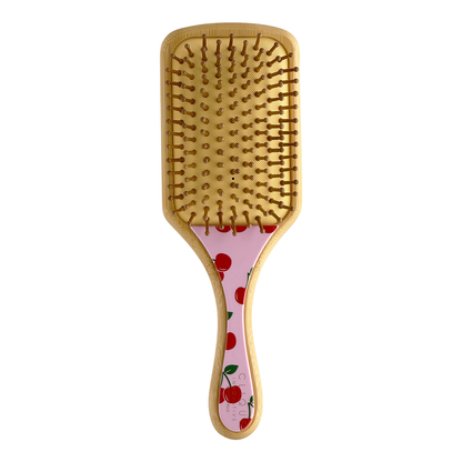 Back view of bamboo paddle hairbrush with bamboo bristles and pink cherries pattern on the handle.