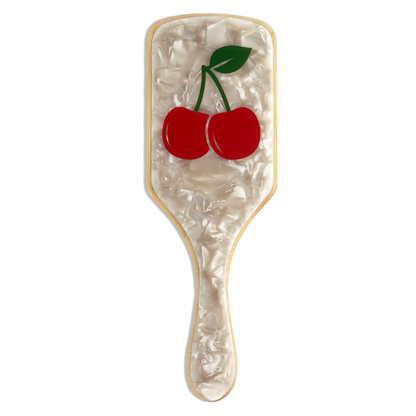Top view of a cherry-design paddle hairbrush featuring a pearl-white marble acrylic surface with two red cherries and a green stem, on a bamboo base.