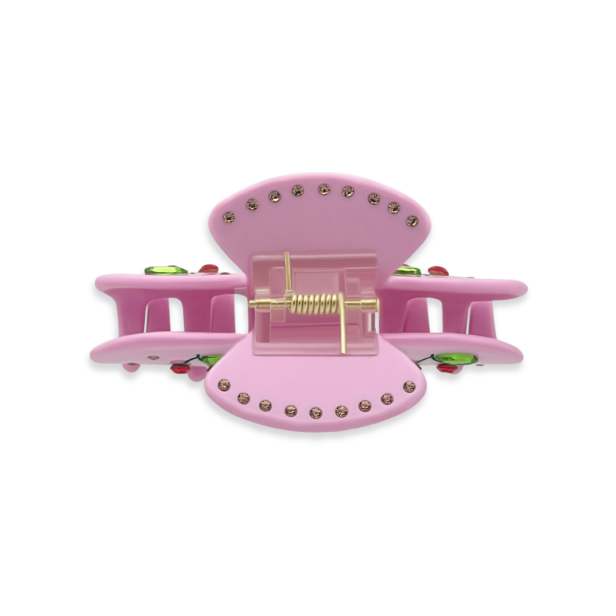 Top view of a pink claw clip showing gold rhinestones along the top edges, a gold spring mechanism, and glimpses of green leaf rhinestones and red cherry details on a white background.