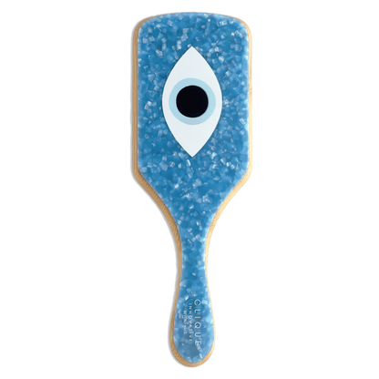 Top view of a blue evil eye paddle hairbrush with bamboo handle from Clique Innovative Beverly Hills.