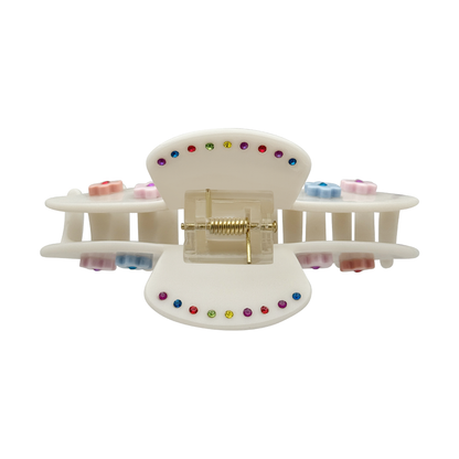 Top view of off-white claw clip with pastel flower accents, multicolor rhinestones, and gold spring hinge detail.