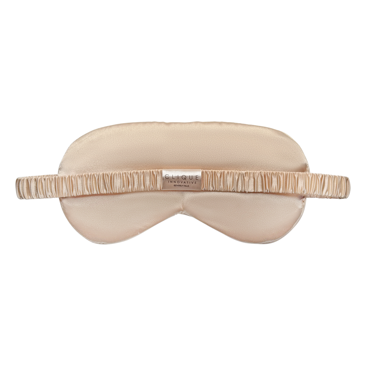 Back view of a champagne gold satin eye mask with a ruched elastic strap and a small “Clique Innovative Beverly Hills” label in the center, shown on a white background.