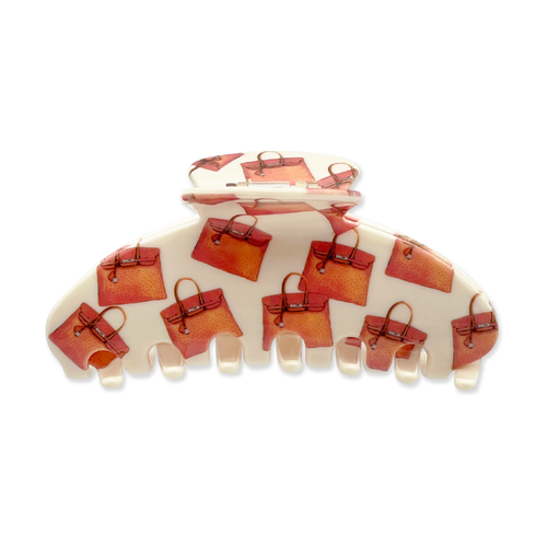 Front view of a beige claw clip with an all-over pattern of orange and red handbag graphics on a white background.
