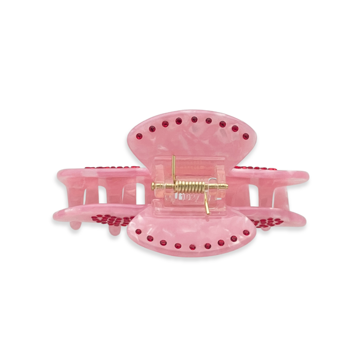 Top view of a pink marble claw clip with red rhinestone accents arranged along the edges on a white background.