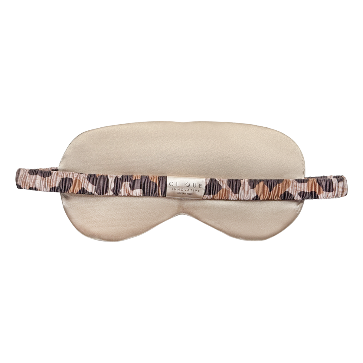 Back view of a beige satin sleep eye mask with a ruched leopard-print elastic strap and a small “Clique Innovative Beverly Hills” label in the center, shown on a white background.