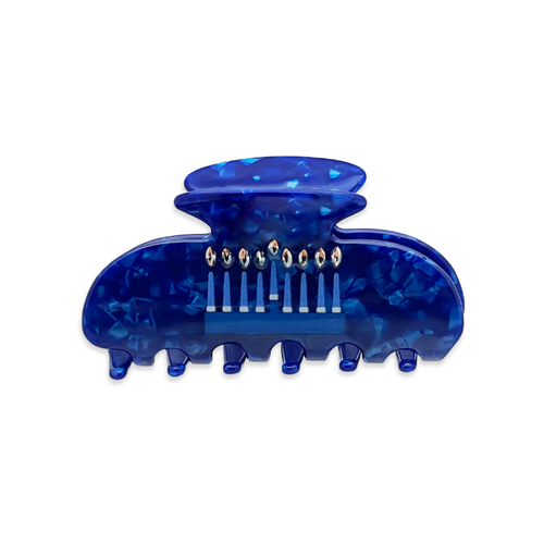 Front view of a dark blue marble claw clip with a menorah graphic featuring lit candles in gold colored rhinestones on the front.