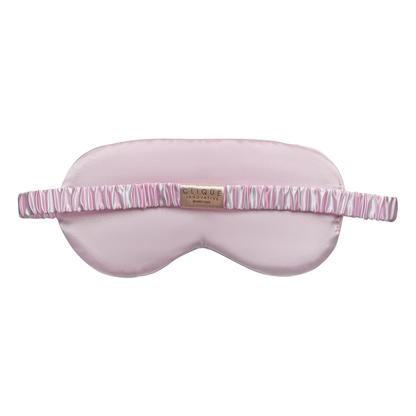 Back view of a light pink satin sleep eye mask with a pink-and-white striped ruched elastic strap and a small ‘Clique Innovative Beverly Hills’ label, shown on a white background.