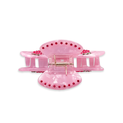 Top view of a pink marble claw clip with red and green rhinestone strawberry accents on a white background.