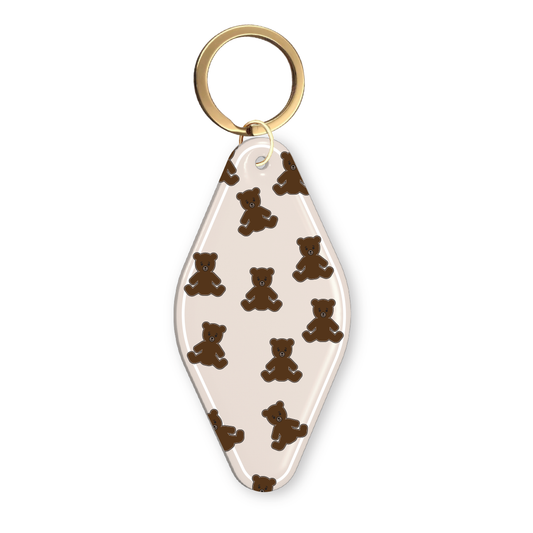 Beige acrylic motel-style keychain with an all-over brown teddy bear pattern and gold keyring.