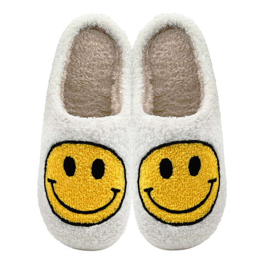 Pair of white plush slippers with large yellow smiley face design.